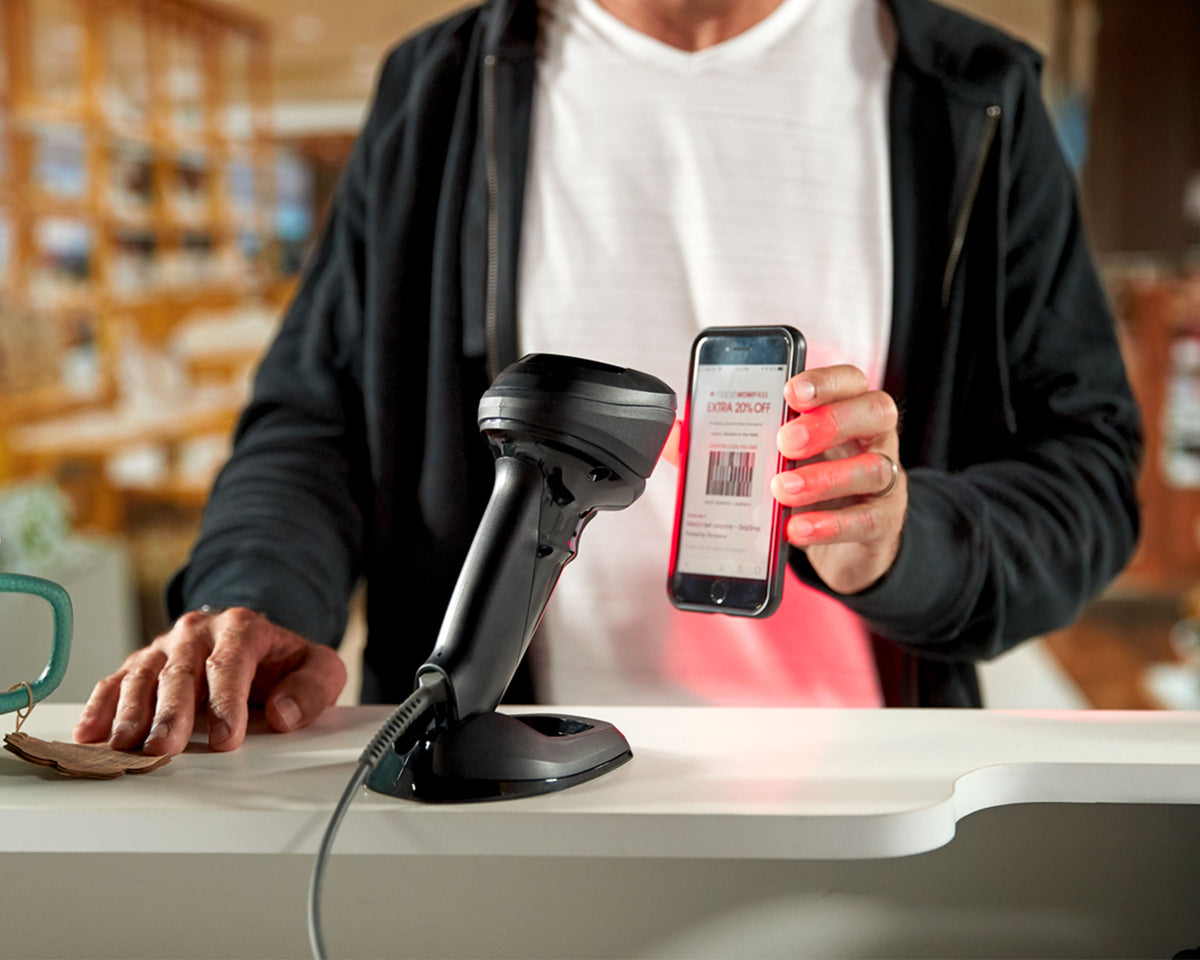 Zebra DS9908 hybrid presentation scanner (DS9908-SR00004ZZWW) – scanning a phone hands-free at a retail counter
